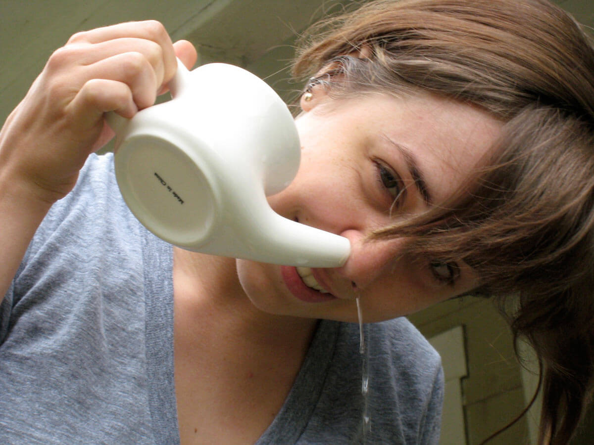 A girl irrigating her sinuses with a neti pot. 